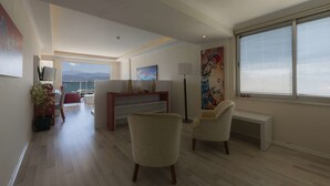 Ein modernes Wohnzimmer mit Meerblick, einem Essbereich und einem großen Fenster mit Jalousien.