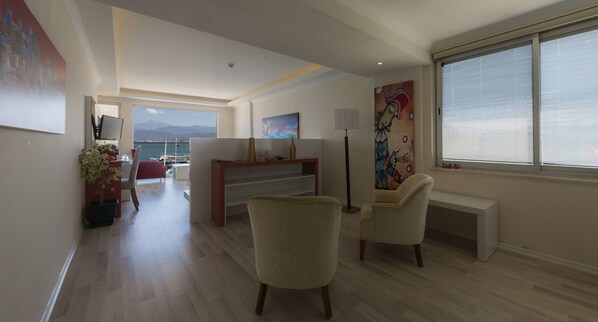 Un vaste espace de vie avec vue sur la mer, un coin repas et un espace détente agrémenté d’une grande fenêtre.