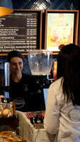 A coffee shop counter with a menu board and a coffee machine.