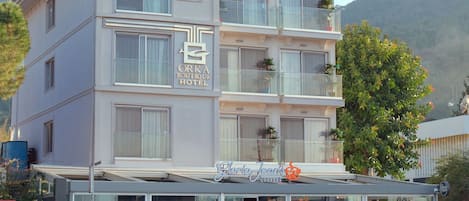 A multi-story hotel with a restaurant on the ground floor, a glass facade, and boats docked in front.