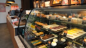 Eine Verkaufstheke einer Bäckerei mit verschiedenen Backwaren und Desserts, darunter Kuchen und Macarons.
