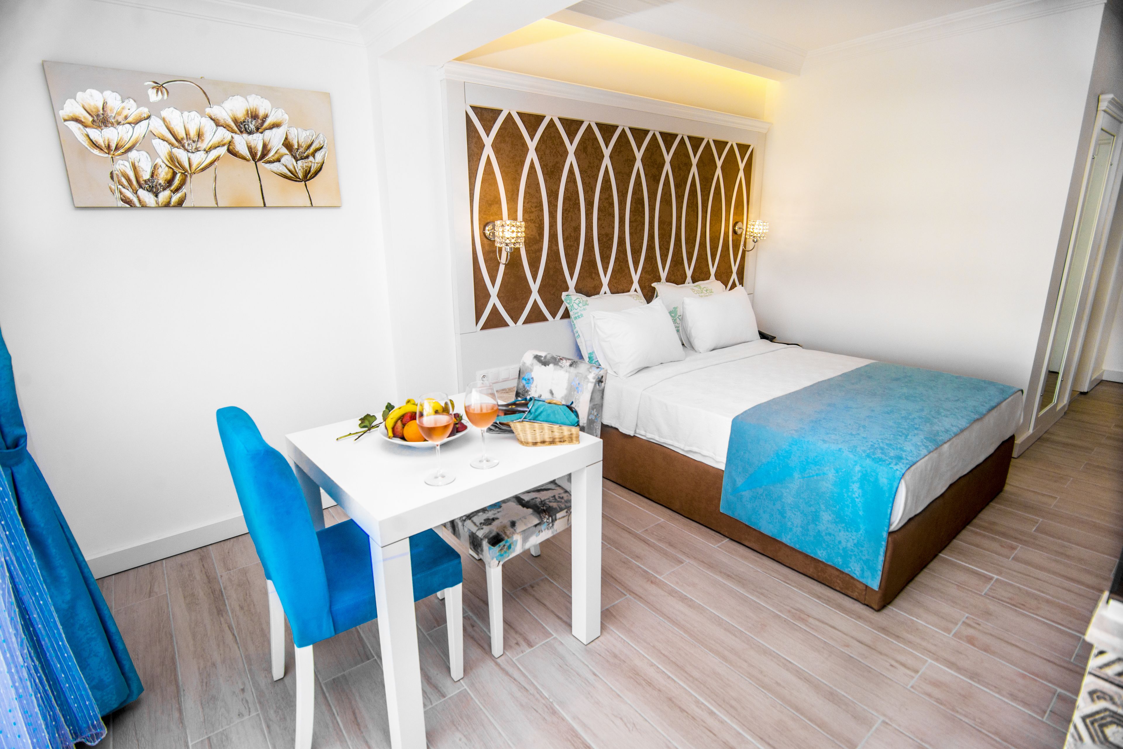 A bedroom with a bed, a table with a chair, and a wall-mounted painting.