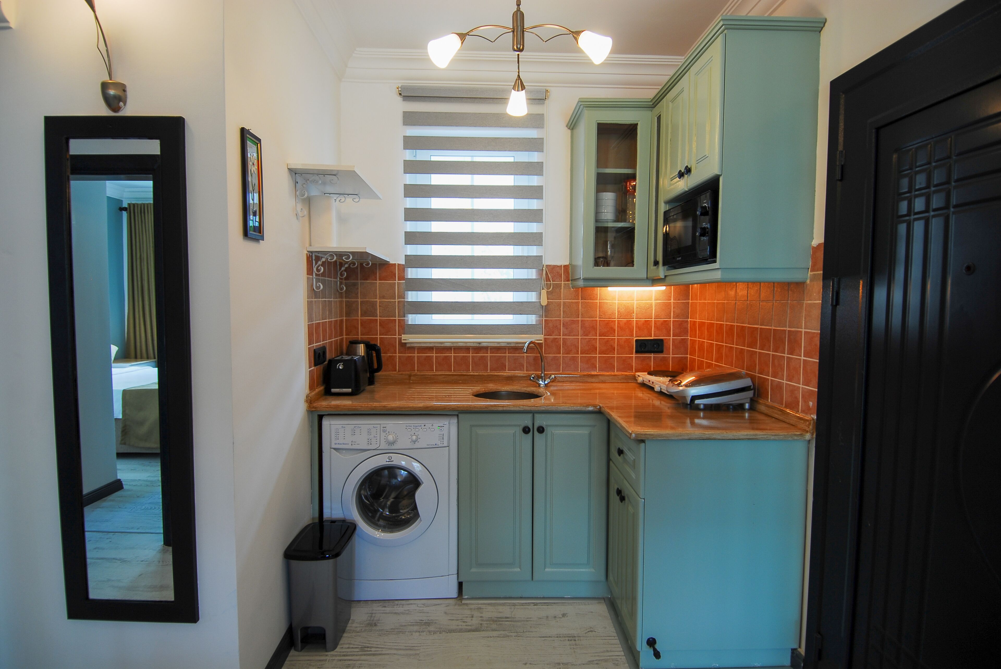 A compact kitchen with a washing machine, a sink, and cabinets.