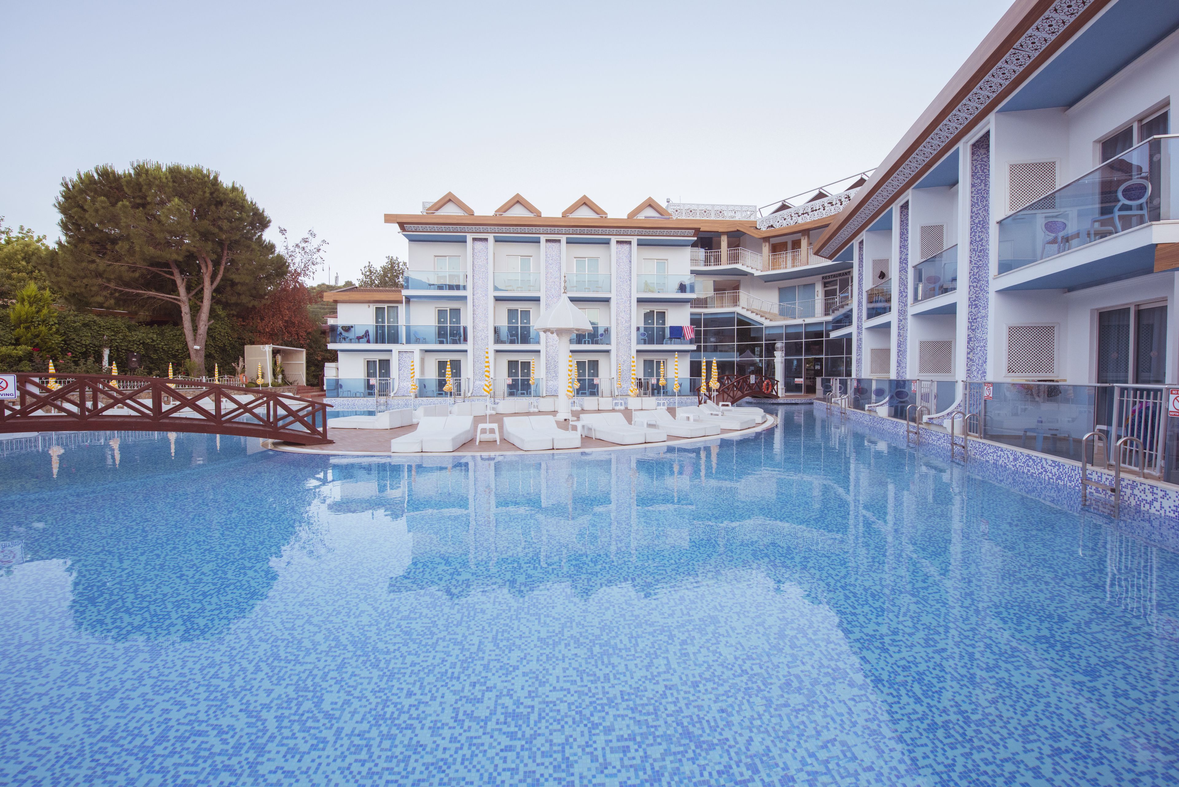 A hotel with a large swimming pool, multiple balconies, and a modern architectural design.