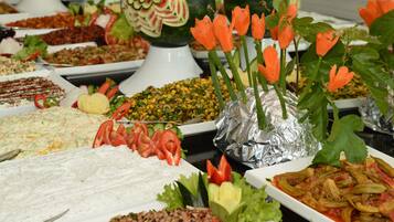 Ein Buffet mit verschiedenen Speisen, darunter Salate, Gemüse und einer Wassermelone als Mittelpunkt.