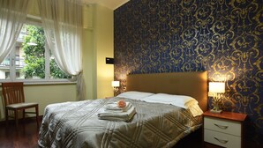 A hotel room with a large bed, a nightstand with a lamp, a chair, and a window with curtains. - B&B Sant'Agostino (Milan)