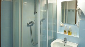 A bathroom with a glass-enclosed shower, a white sink, and a mirror above it. - B&B Sant'Agostino (Milan)