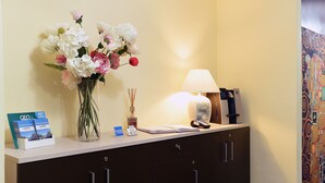 A reception desk with a vase of flowers, a lamp, a brochure, and a phone. - B&B Sant'Agostino (Milan)