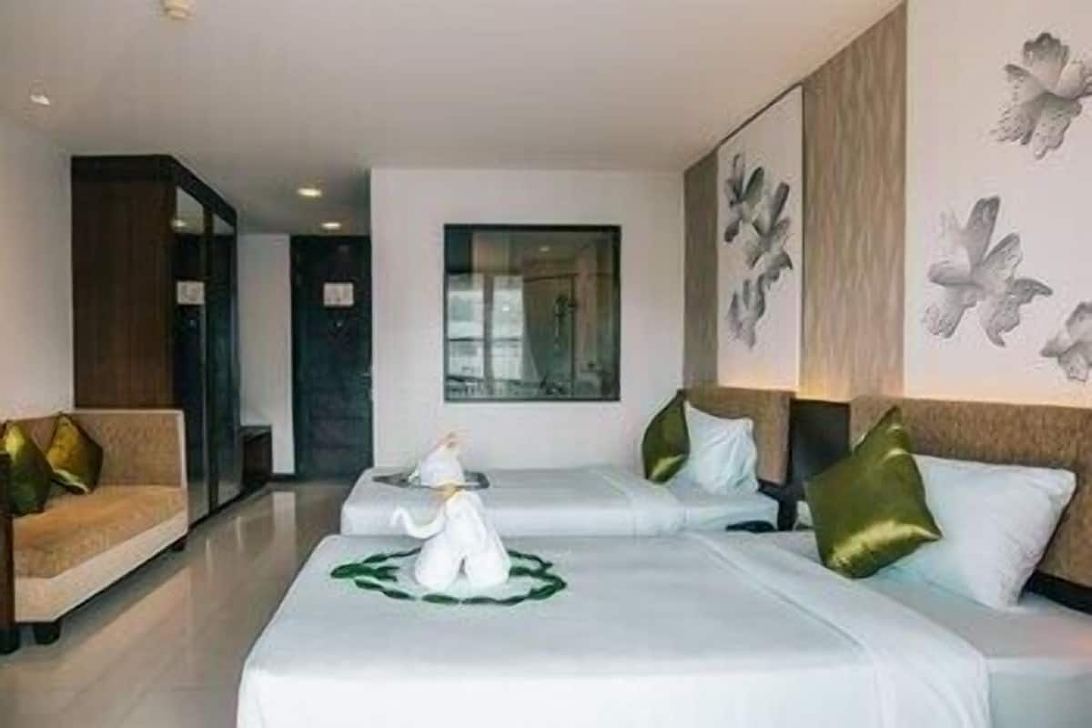 A hotel room with two beds, a sofa, and a painting of birds on the wall.