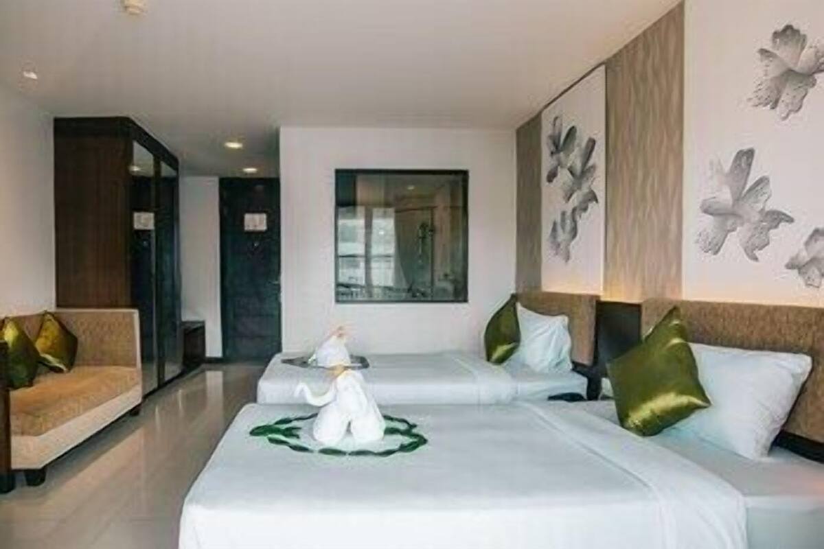 A hotel room with two beds, a sofa, and a painting of birds on the wall.