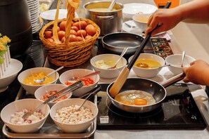 A kitchen counter with various cooking ingredients and utensils, including bowls of chopped vegetables, eggs, and a frying pan.