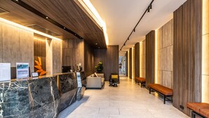 A modern lobby with a marble reception desk, seating area, and wooden paneling. - Citrus Patong Hotel by Compass Hospitality (Patong)