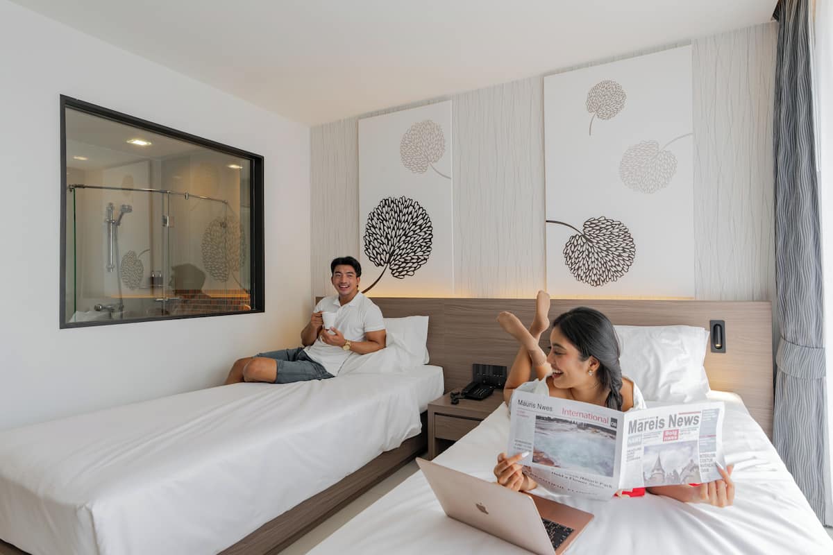 A hotel room with two beds, a large mirror, and wall art depicting abstract floral designs.