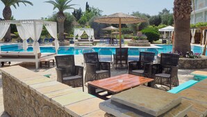 A poolside area with lounge chairs, a wooden table, and a canopy. - Hotel Paloma Blanca (Corfu)