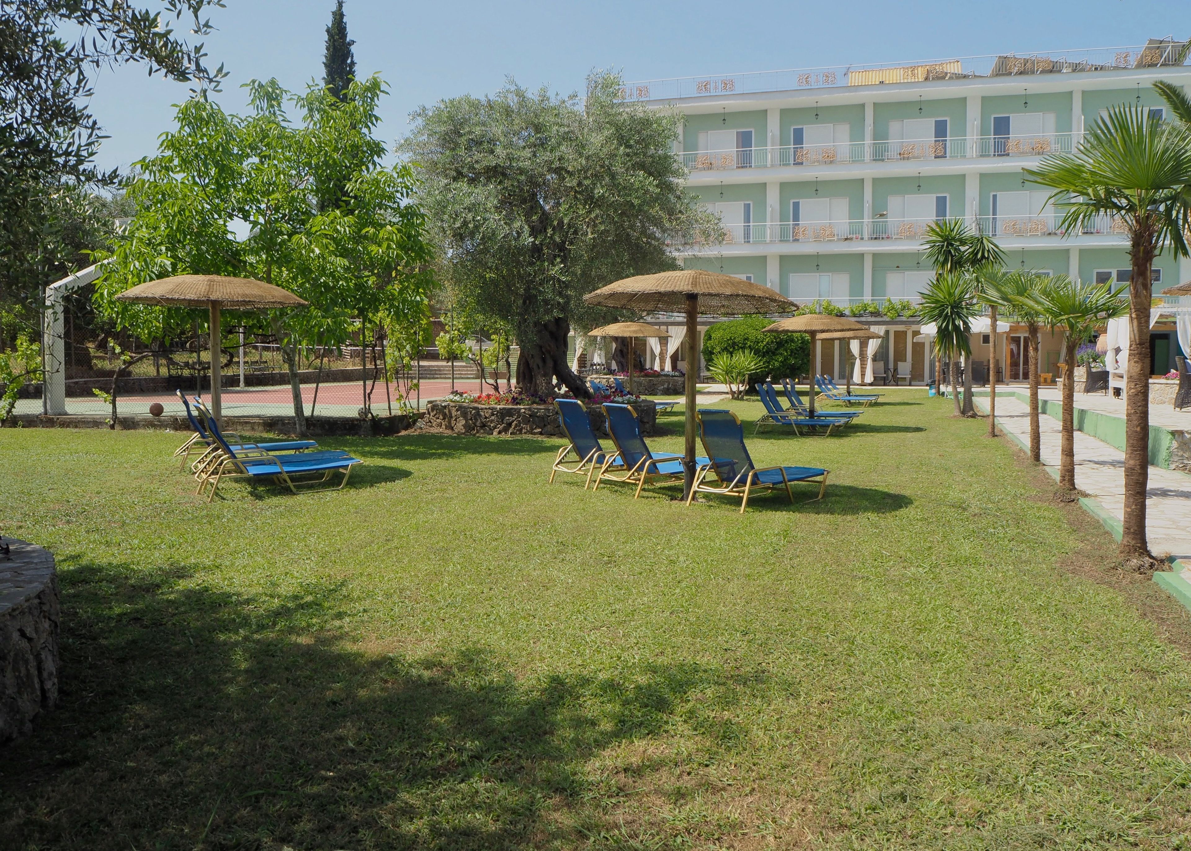 A courtyard with sun loungers, umbrellas, and a building with balconies in the background.