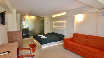 Una habitación de hotel moderna con cama, sofá, escritorio y silla.