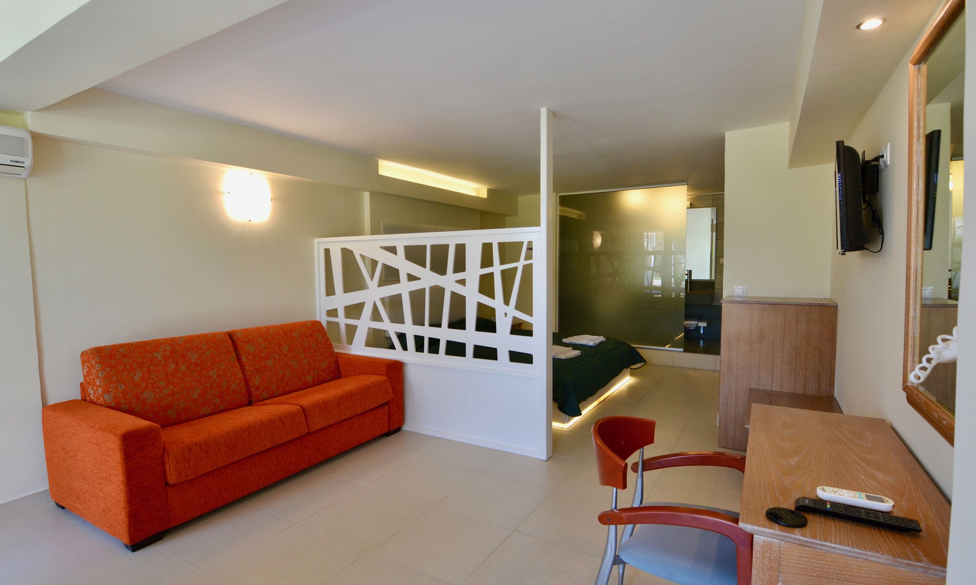 A hotel room with a sofa, a desk, a chair, and a bed.