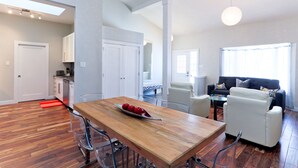A spacious living area with a wooden dining table, a sofa, and a coffee table. - Boardwalk Homes - Executive Guest Rooms & Townhomes (Kitchener)