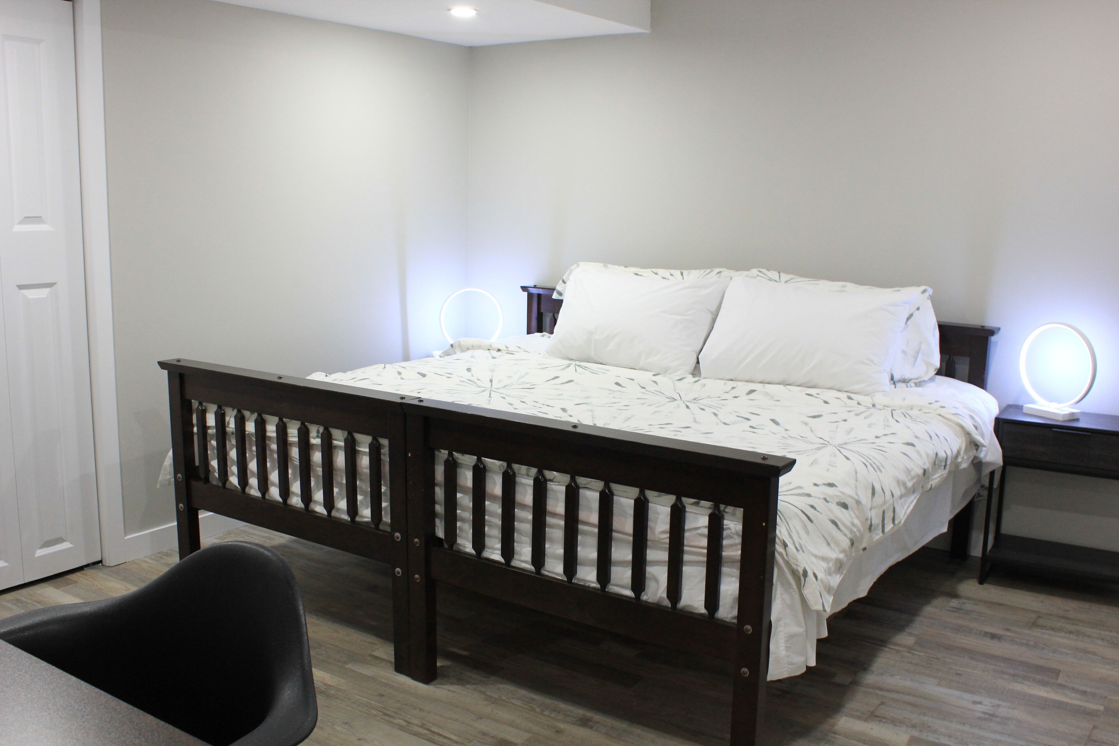 A bedroom with a bed, bedside tables, and a chair.