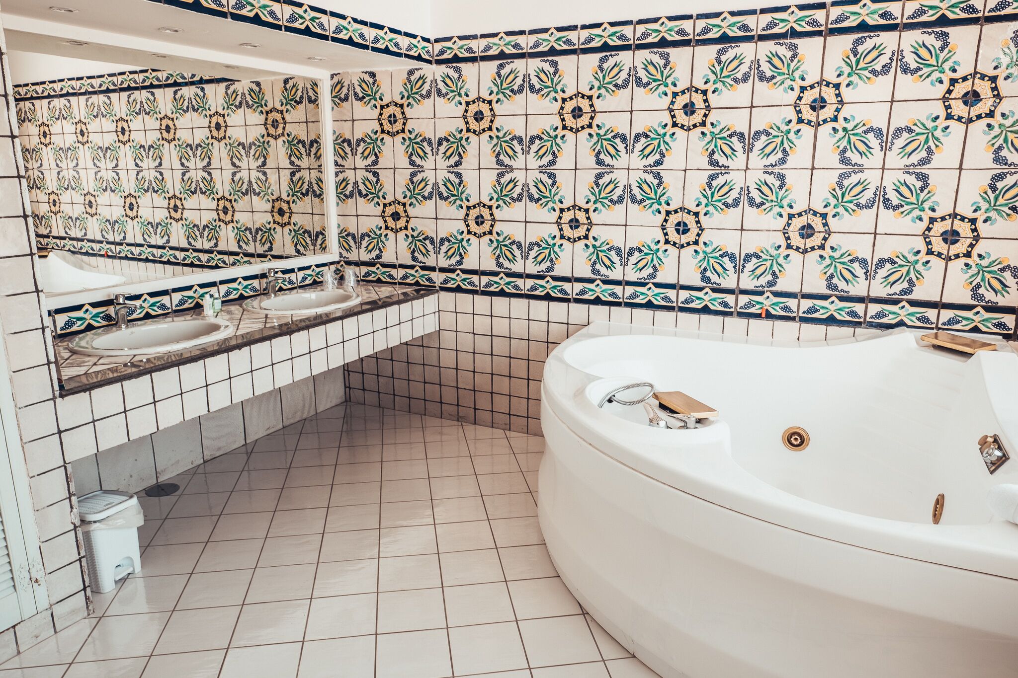Un baño con una bañera grande, dos lavamanos y azulejos decorativos.
