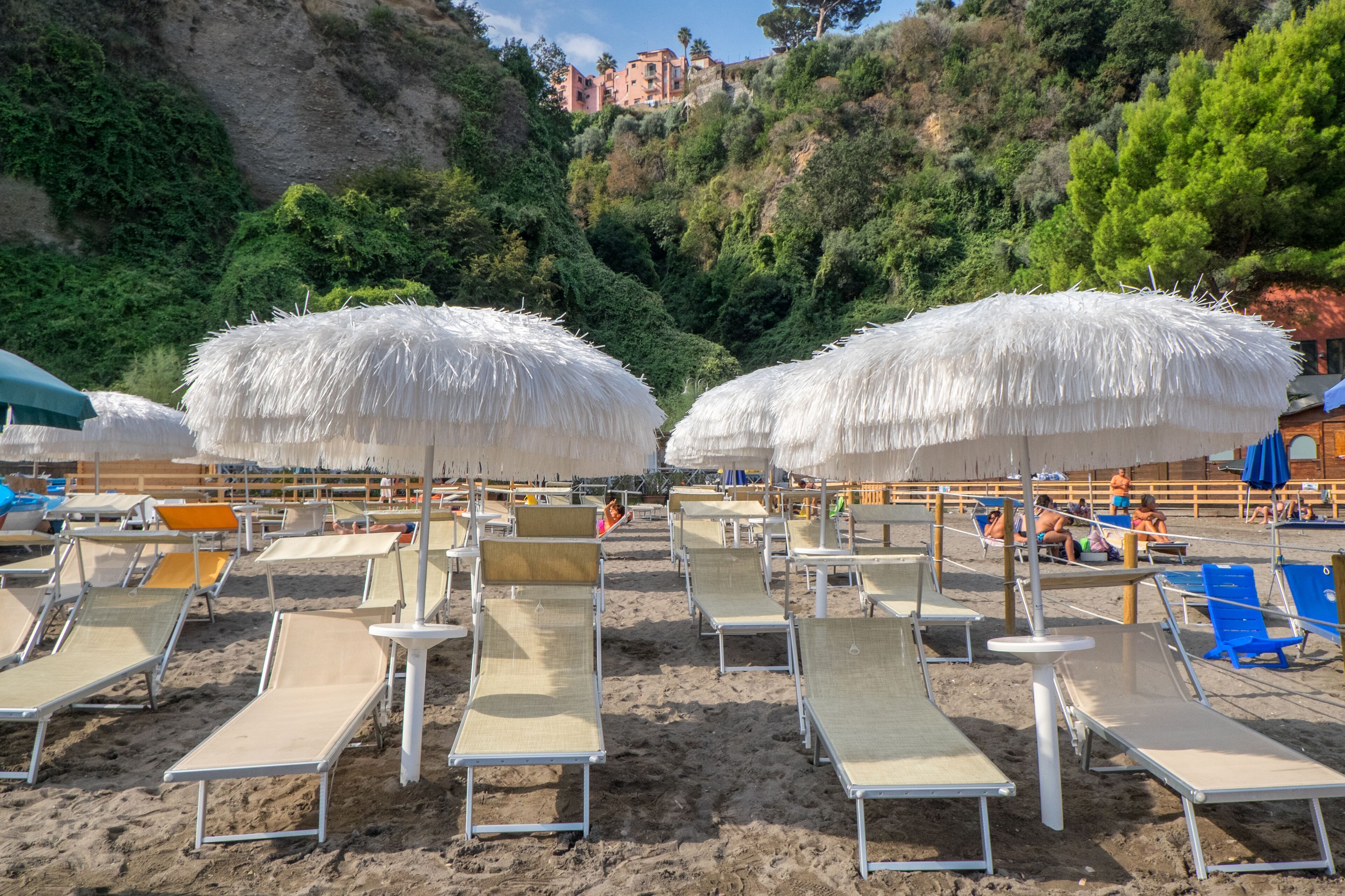 A beach with rows of sun loungers and thatched umbrellas.