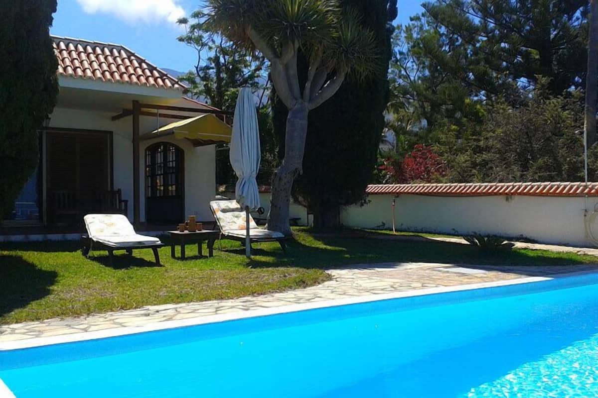 A swimming pool with lounge chairs and a covered patio area.