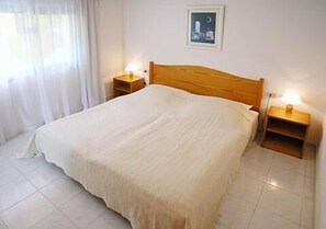 A neatly made bed with a wooden headboard, two bedside tables with lamps, and a framed picture on the wall. - Residencial Las Norias (Los Llanos de Aridane)