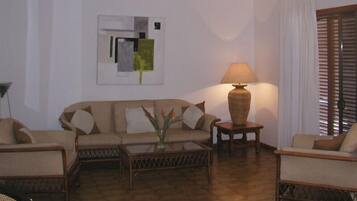 Ein Wohnzimmer mit einer Couch, Sesseln, einem Couchtisch und einer Lampe.