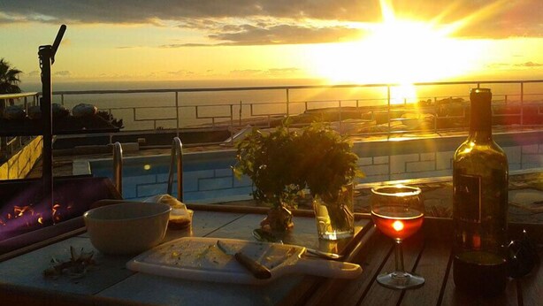 A sunset view from a balcony with a pool, a bottle, and a glass. - Residencial Las Norias (Los Llanos de Aridane)