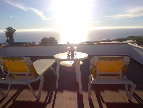 Terraza con dos sillas y una mesa, con vista a un cuerpo de agua.