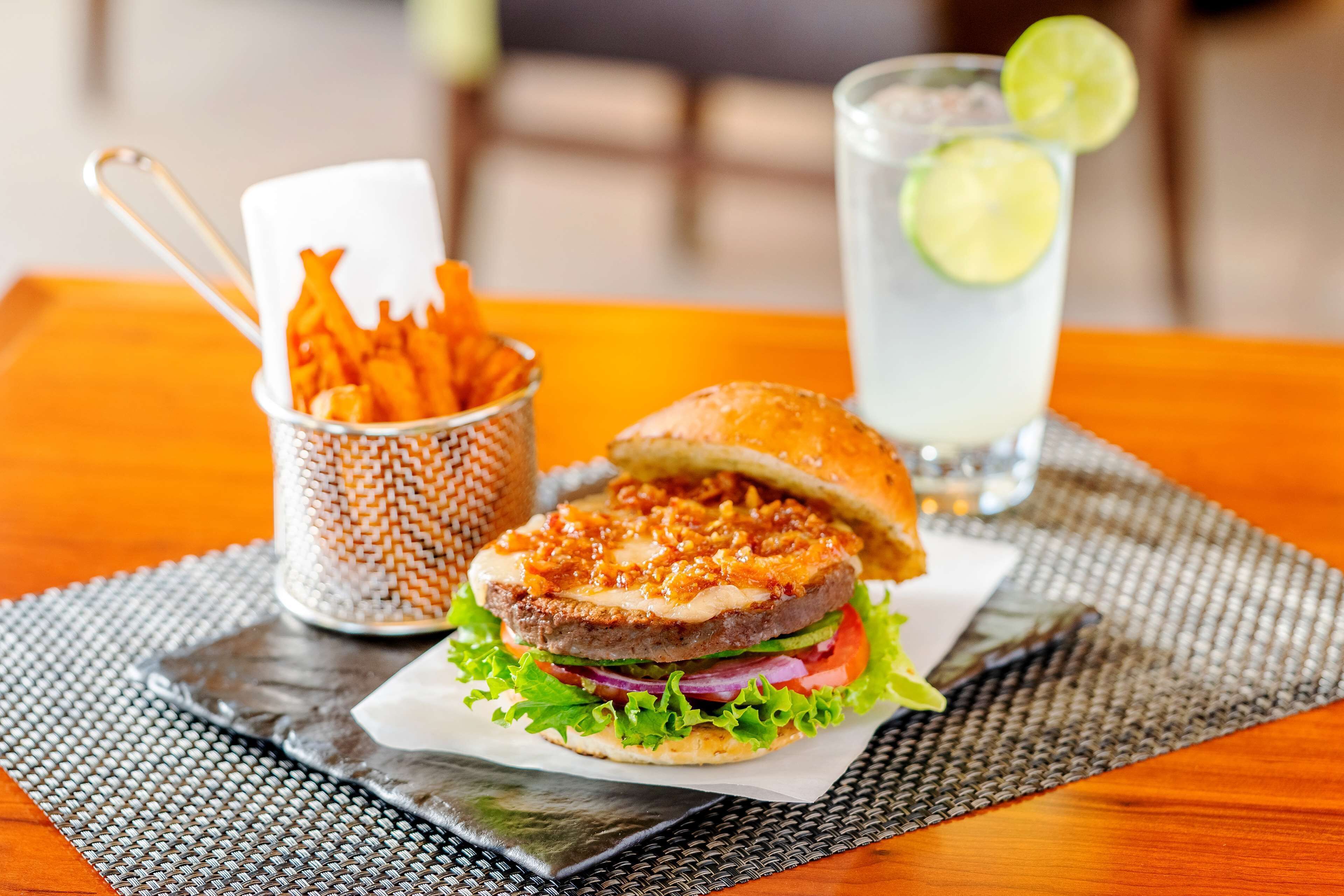 A burger with fries and a drink on a table.