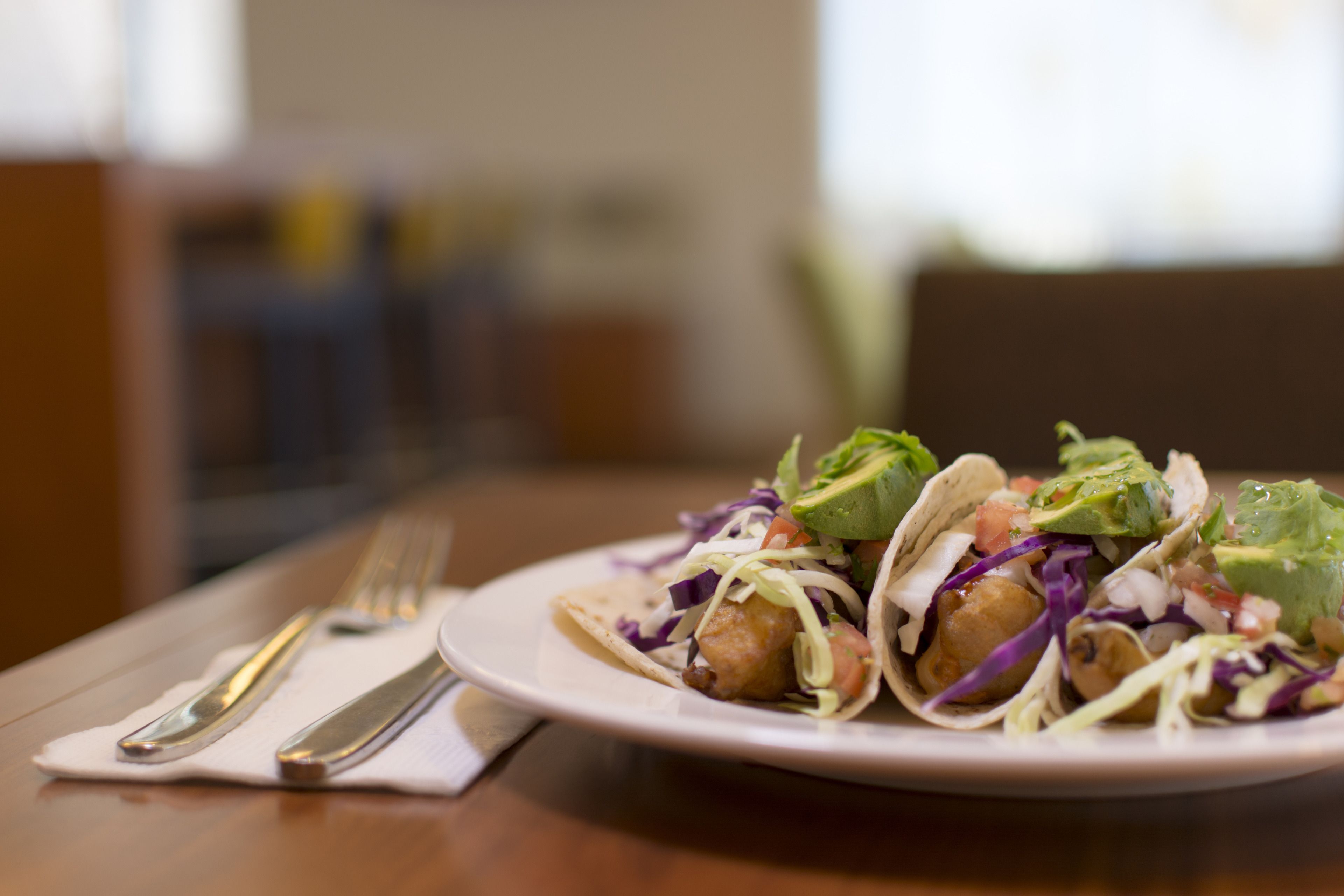 A plate of tacos with a fork and knife on a table.