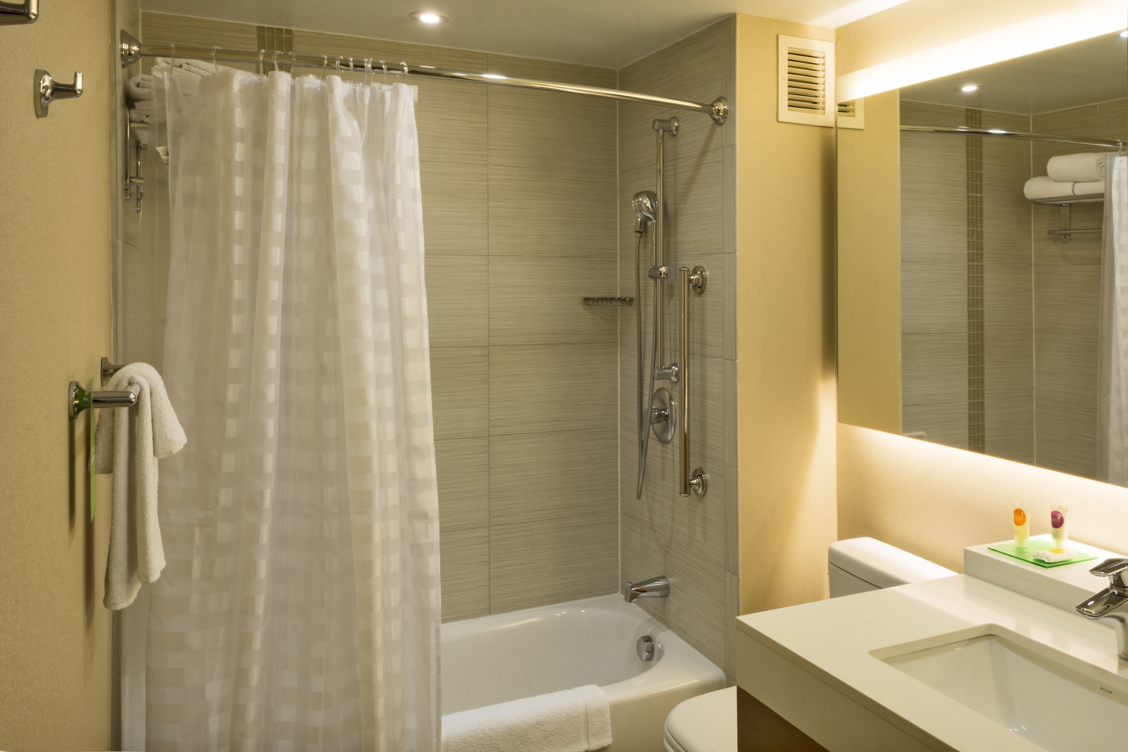 Un baño moderno con ducha envuelta en vidrio, una bañera blanca y un lavamanos con espejo.