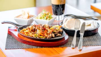 Un repas composé d’un steak et de légumes, accompagné d’une boisson, le tout servi sur une table avec des couverts.