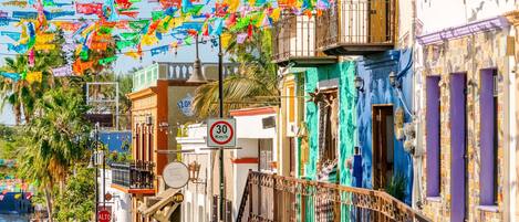 A street with colorful flags, a pharmacy, and a speed limit sign.