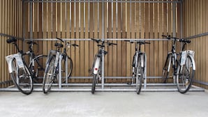 A bike rack with five bicycles parked in an indoor facility with wooden slats on the walls. - The Corner London City (London)