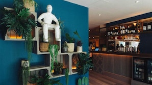 A bar area with shelves of plants and a white statue. - The Corner London City (London)