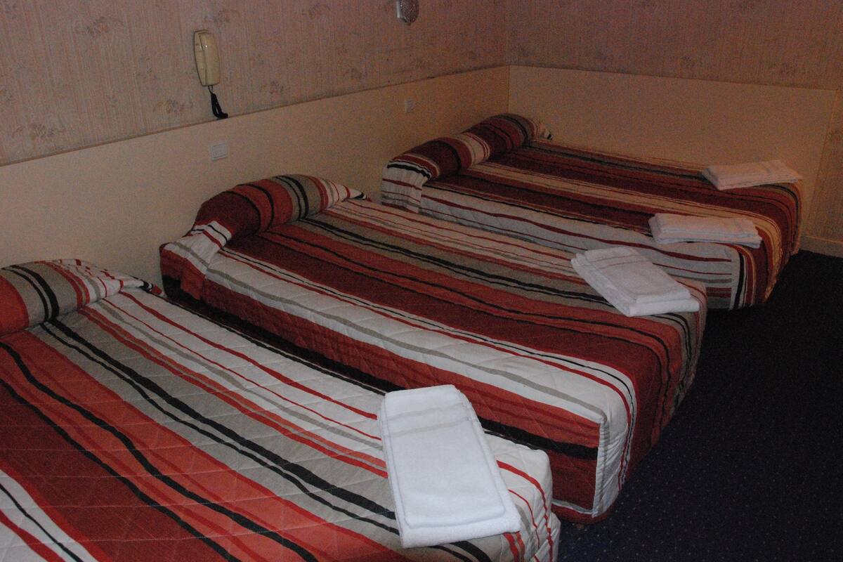 A hotel room with two beds, each with striped bedding and a folded towel on the side.