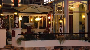 Un restaurant en plein air avec des murs en pierre, des tables à l’extérieur et des statues décoratives.