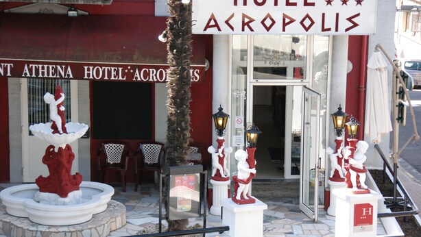 L’extérieur de l’hôtel Acropolis, avec sa fontaine, ses espaces de détente en plein air et ses statues décoratives.
