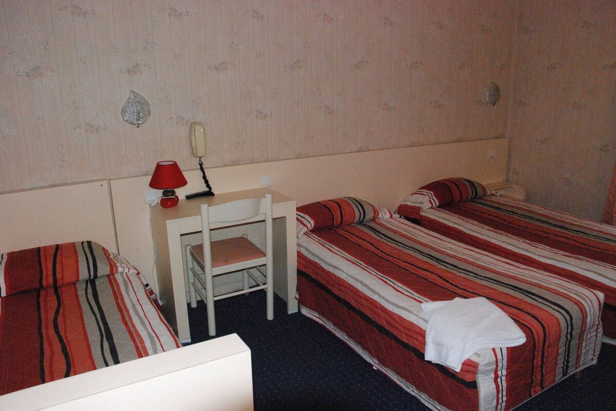 A room with two beds, a desk, and a chair.