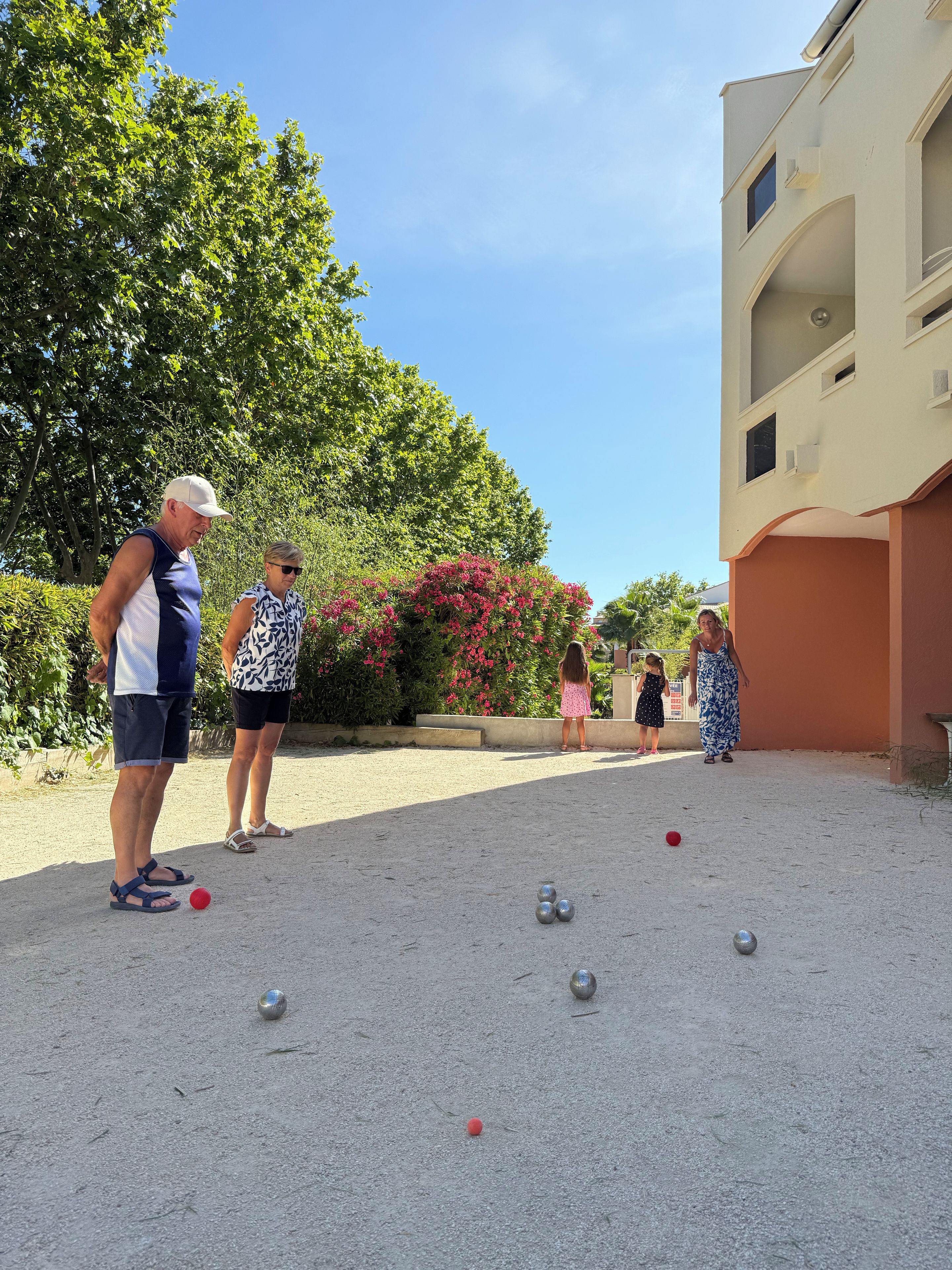Et udendørs område med boccebane, en bygning med flad facade og en klar himmel.
