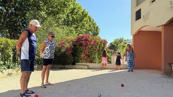Et udendørs område med boccebane, en bygning med flad facade og en klar himmel.