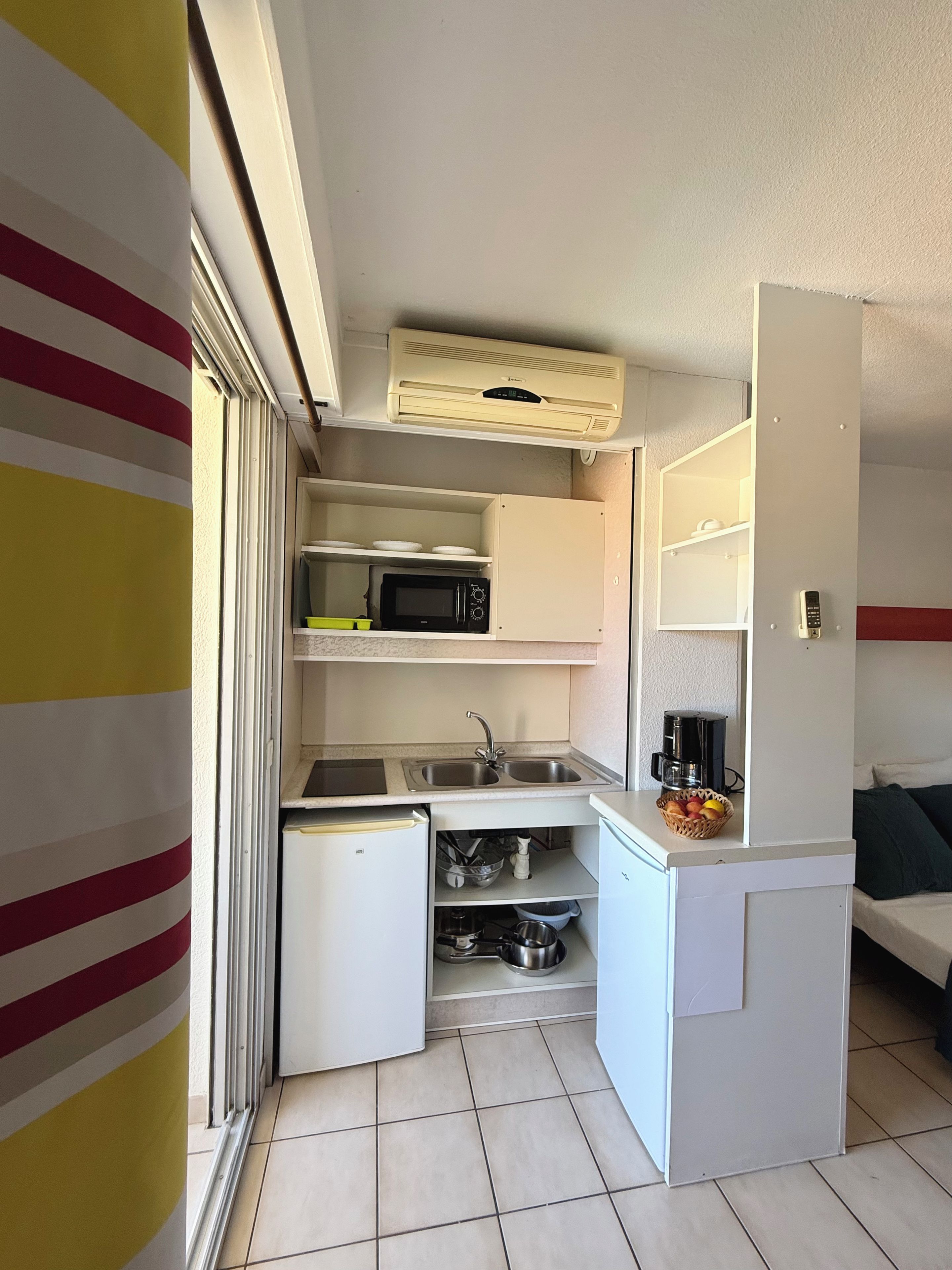 A compact kitchenette with a microwave, sink, and a small refrigerator.