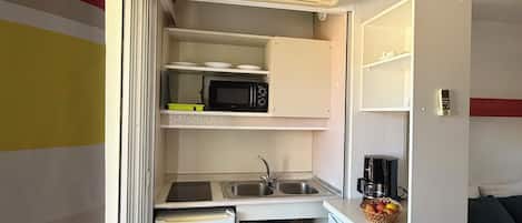 A compact kitchenette with a microwave, sink, and a small refrigerator.