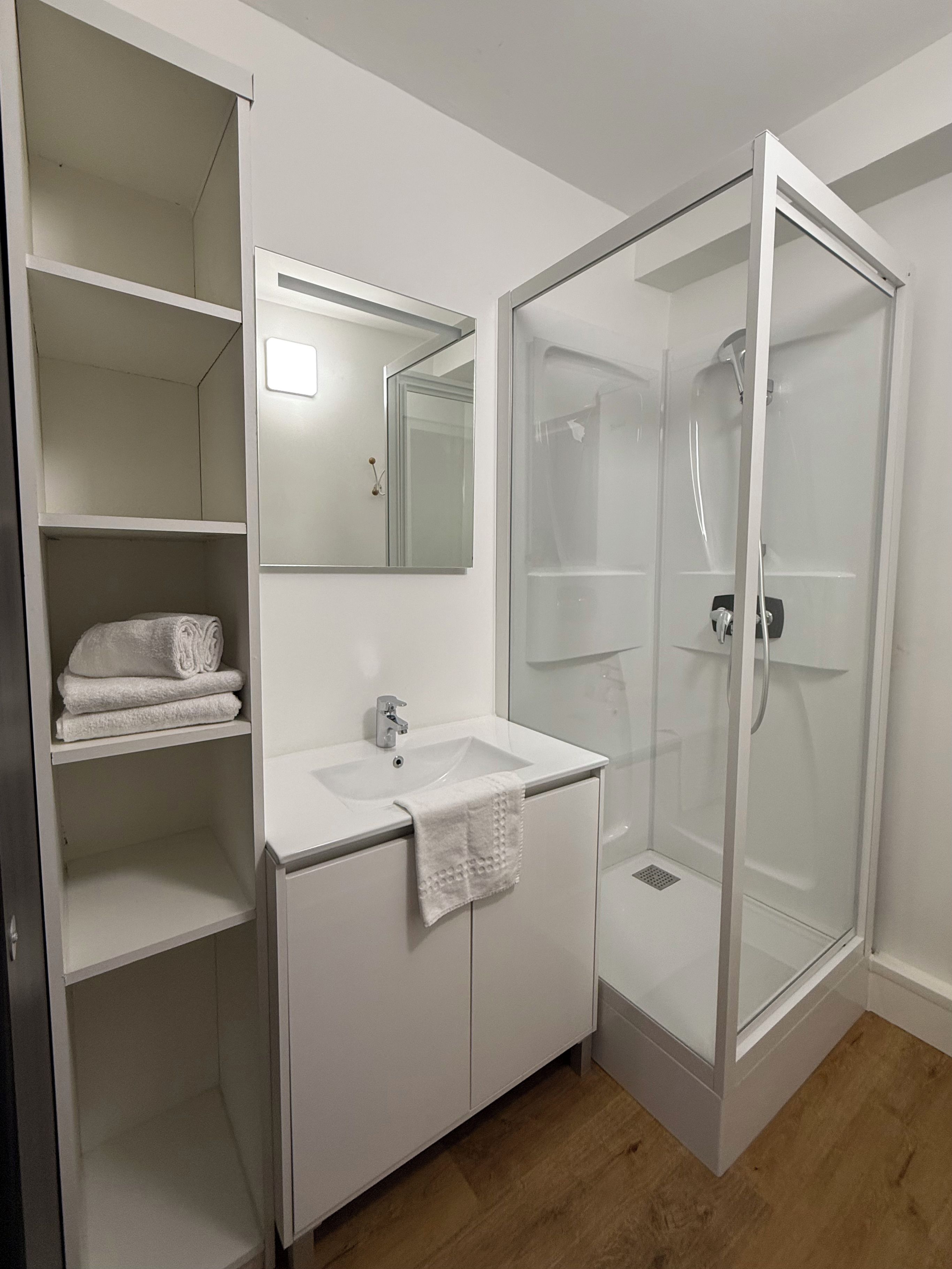 A bathroom with a white sink, mirror, and glass-enclosed shower.