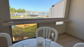 Un balcón con mesa, sillas, un frutero y vista al puerto deportivo.