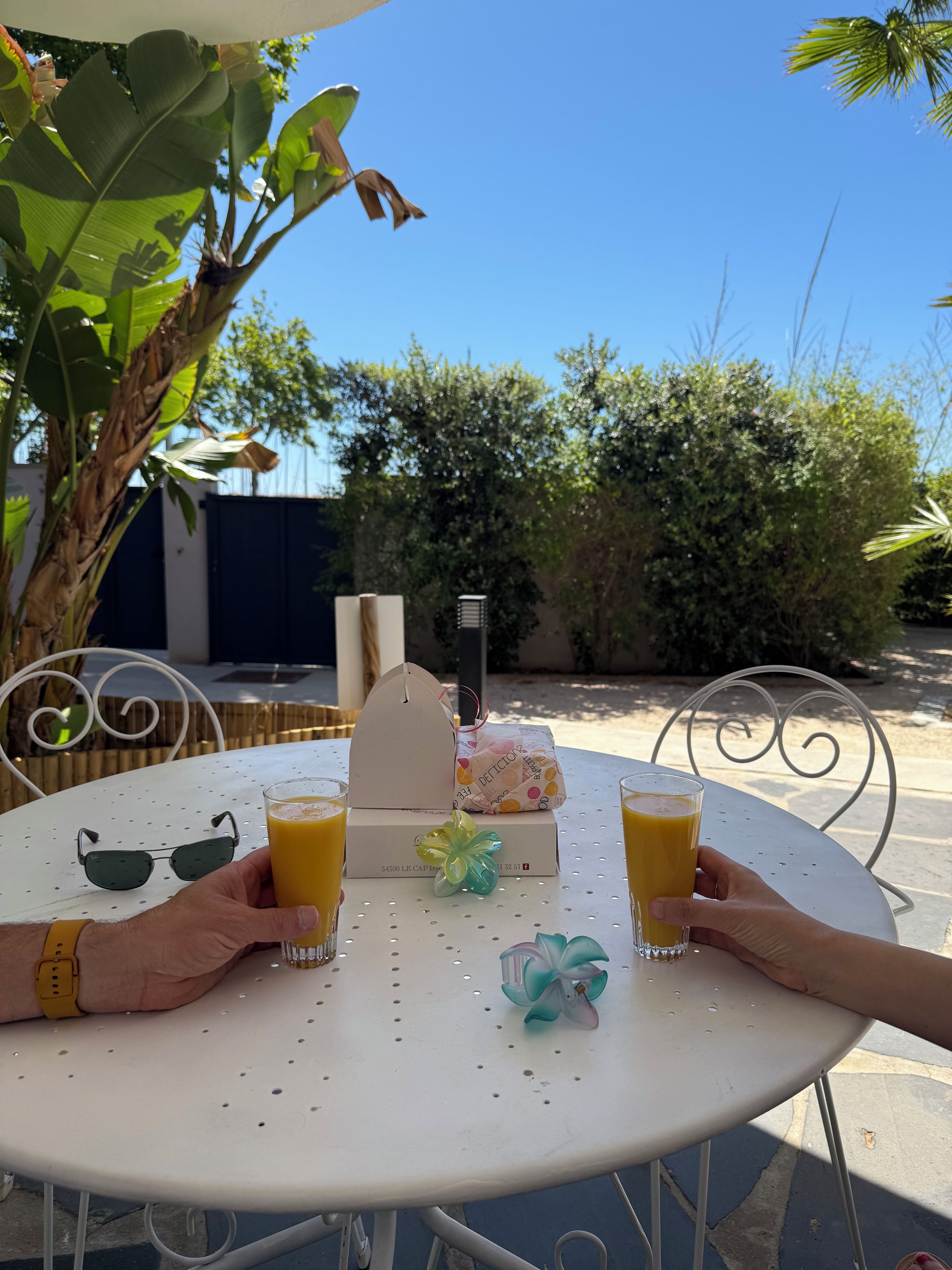A round table with two glasses of orange juice, a small decorative item, and a white box with a handle.