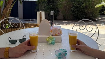 A round table with two glasses of orange juice, a small decorative item, and a white box with a handle.