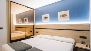 Una camera d'albergo con un letto grande, un comodino, uno specchio e opere d'arte appese al muro.